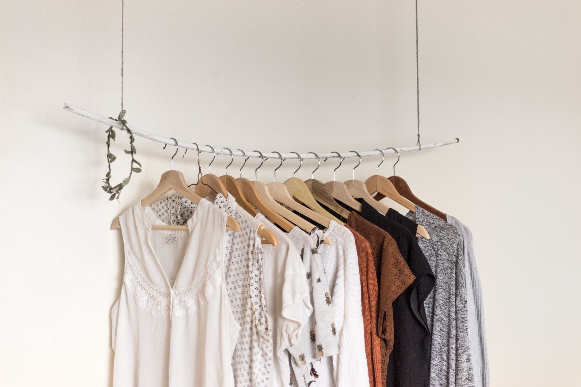 Capsule rack of garments hanging on a white wall